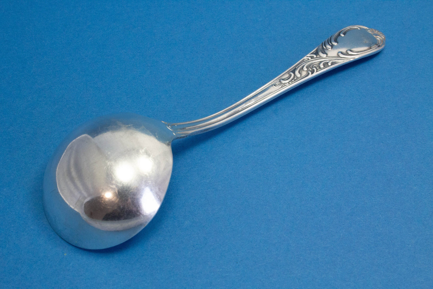 Versilberter Sahnelöffel mit Rokoko-Verzierungen